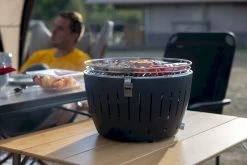 LotusGrill XL Hybrid Houtskoolbarbecue - Rood -Winkel Voor Kampeerartikelen Voor Buiten lotusgrill in gebruik met toppy shirtje 2